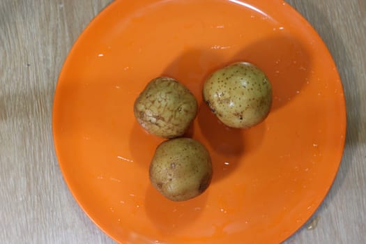 Potato on a orange color cutting board.
