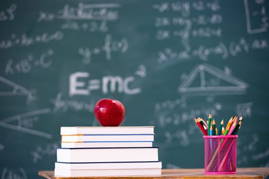 Back to School Concept. Apple, accessories and books against chalkboard.