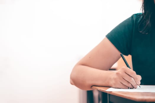High school or university student holding pencil writing on paper answer sheet. Final exam concept.