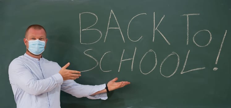 Teacher with face mask welcoming children back at school after lockdown. Back to school during COVID-19 pandemic.