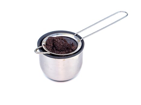 A strainer for filtering coffee or tea is poured into a cup. Metal strainer. Coffee and hot drinks. Preparing hot drinks. Filter. Kitchen dishes. Home kitchen. Tool. White background. Place for text.