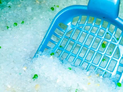 Cat litter box with white filler and paddle. Pet care. The cat's toilet. Silicon granular filler. Pet hygiene. Sanitation. Clean paws. Domestic life of animals. Background image.
