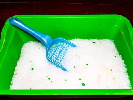 Cat litter box with white filler and paddle. Pet care. The cat's toilet. Silicon granular filler. Pet hygiene. Sanitation. Clean paws. Domestic life of animals. Background image.