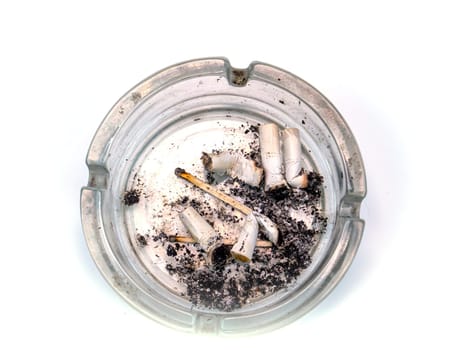 Glass ashtray with cigarette butts on a white background. The harm of smoking. Ashtray made of transparent glass. Nicotine in a cigarette. Fmltr cigarettes. Ash from the butt. Healthcare and health.