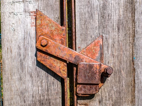 Old rusty iron bolt of a wooden gate lock. Rusty lock of wooden doors. Aging of metal. Safety. Wood material. Background image. Place for your text. Retro style.