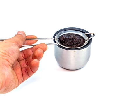 A strainer for filtering coffee or tea is poured into a cup. Metal strainer. Coffee and hot drinks. Preparing hot drinks. Filter. Kitchen dishes. Home kitchen. Tool. White background. Place for text.
