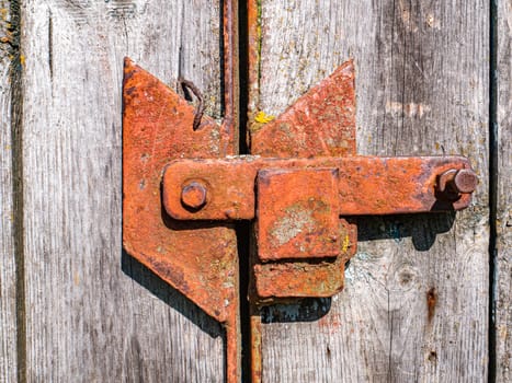 Old rusty iron bolt of a wooden gate lock. Rusty lock of wooden doors. Aging of metal. Safety. Wood material. Background image. Place for your text. Retro style.