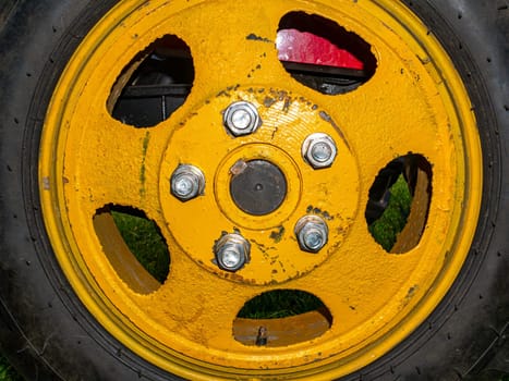 Agricultural tractor wheel with yellow disc on nuts. Fastening the vehicle wheel. Tire service. Rubber tire. Car repair. Car service. Place for your text. Nut bolts. Background image.