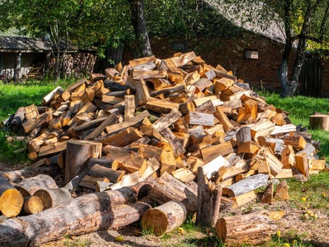 A pile of wood chopped with an ax for the heating season. Harvesting pine firewood for a wood stove. Winter heating season in a village house. Timber processing industry. Ignite the hearth.