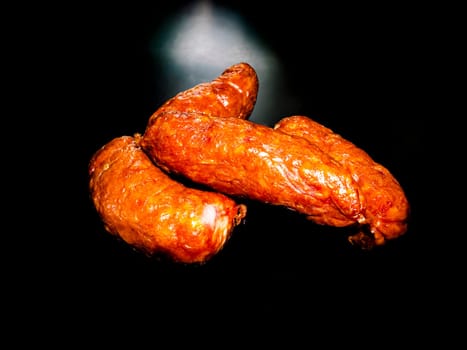 Smoked meat sausages on a black background. Food photo. Recipe. Smoked meat. Fatty food. Home kitchen. Menu of dishes. Advertising photo of the store. Place for text. Poster.