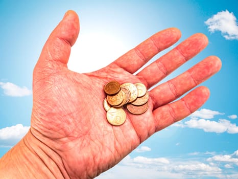 Hand with money coins on a background of blue sky. God's gift. Prayer. Request for help. Asking for money. Giver's hand. Sunbeams. Euro money. Background image. Place for text. Poster.