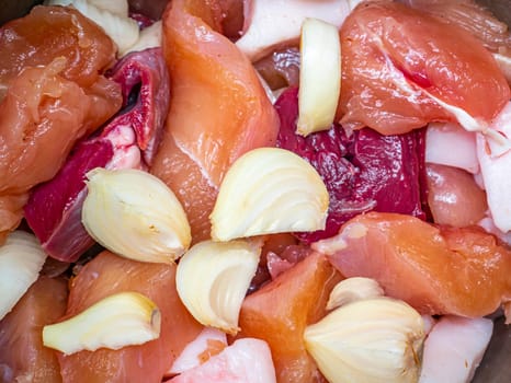 Chunks of raw meat with onions for cooking. Food photo. Meat dish. Preparing food. Cutting meat. Butcher's job. Home kitchen. Recipe. Raw meat. Chicken's meat.