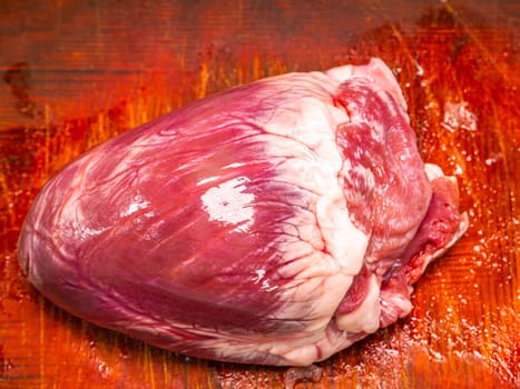 Pork heart on a wooden cutting board. Food photo. Meat dish. Preparing food. Cutting meat. Butcher's job. Home kitchen. Recipe. Raw pork meat. Animal heart.