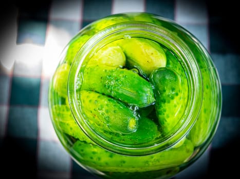 Canned cucumbers in a glass jar on the table. Food photo. Agriculture. Farm. Shop window photo. Preservation of cucumbers. Pickled vegetables.