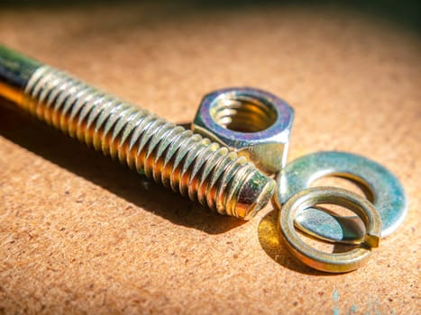 Bolt and nut on a wooden table macro photo. Iron bolt. Washer under the nut. Locksmith material. Wooden background. Macro photography. Background image. Place for text.