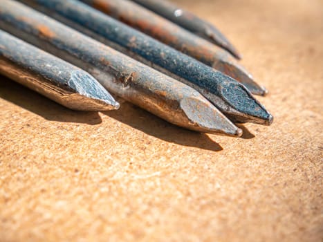 Iron nails on a wooden table macro photo. Nail head. Sharp tip. Joiner's material. Wooden background. Macro photography. Background image. Place for text.