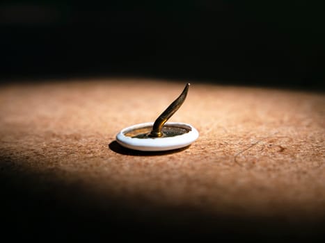 Bent pushpin on wooden table macro photo. Stationery. Background image. Place for text. Sharp. Closeup.