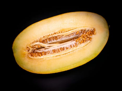 Yellow melon cut with a knife on a black background. Food photo. Melon culture. Agriculture. Place for your text. Black background. Background image. Shchablon. Poster. Vegetarian food.