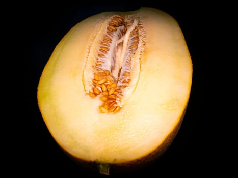 Yellow melon cut with a knife on a black background. Food photo. Melon culture. Agriculture. Place for your text. Black background. Background image. Shchablon. Poster. Vegetarian food.