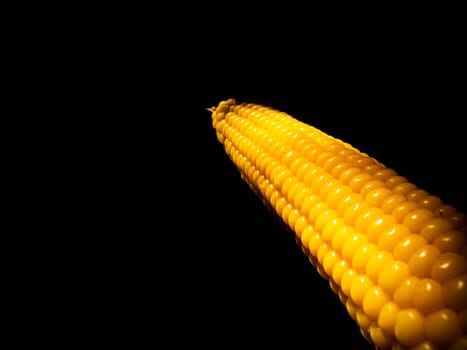 Yellow swing of corn on a black background. Boiled corn. Harvest. Agriculture. Food photo. Black background. Place for your text. Background image. Poster. Vegetarian food.