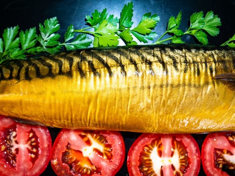 Smoked mackerel fish with tomatoes on a black background. Salted mackerel fish. Green parsley. Canned food. Food photo. Recipe. Menu of dishes. Vegetarian food. Home kitchen. Fishing.