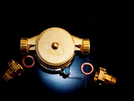 Water meter with threaded connection for nuts. Black background. Plumbing equipment. Plumbing repair. Plumbing repairman. Pipeline. Background image. Place for your text.