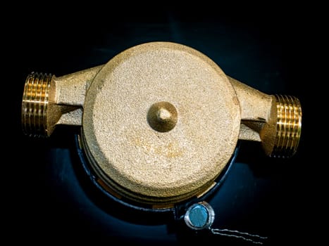 Water meter with threaded connection for nuts. Black background. Plumbing equipment. Plumbing repair. Plumbing repairman. Pipeline. Background image. Place for your text.