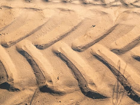 Car wheel tread trace on the sand. Freight road transport. Ride an all-terrain vehicle on the sand. Motor commercial transport. Wheel tire tread marks. Place for your text. Background image.