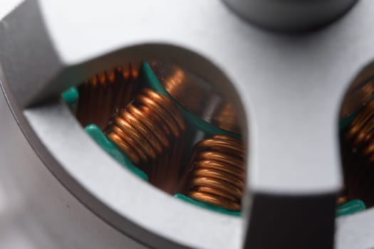 Closely looking down into tall copper coils or stators within a brushless electric drone motor. Three color metallic theme, very detailed close up.