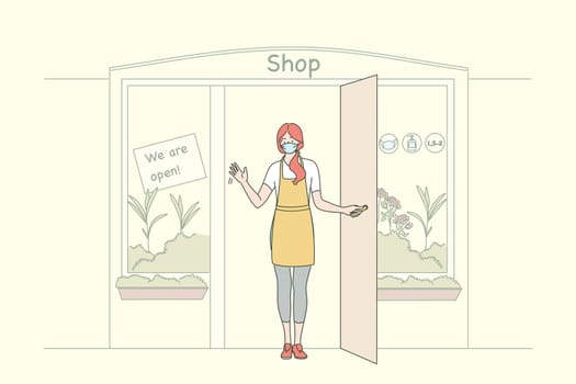 Reopening doors after COVID-19 outbreak concept. Young woman shop worker greeting new customers from door and wearing face medical mask for protection from coronavirus infection
