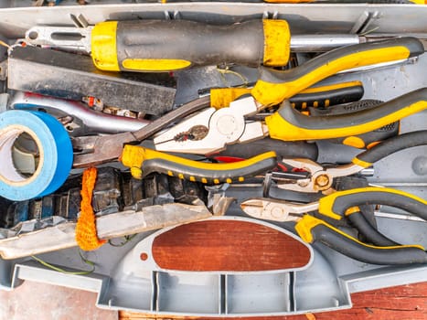 Plastic case with a working locksmith tool. Pliers and screwdrivers. Spanners. Electrical tape and knife. Locksmith accessories. Worker tool. Background image. Place for your text.