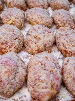 Meat cutlets sprinkled with white flour on the kitchen table. Culinary recipe for meat cutlets. Cooking food. Home kitchen. Menu of dishes. Cutting board. Background image.