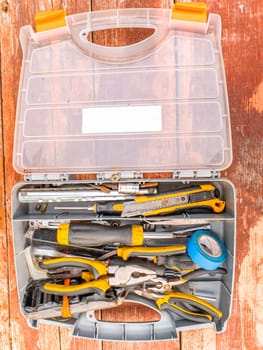Plastic case with a working locksmith tool. Pliers and screwdrivers. Spanners. Electrical tape and knife. Locksmith accessories. Worker tool. Background image. Place for your text.