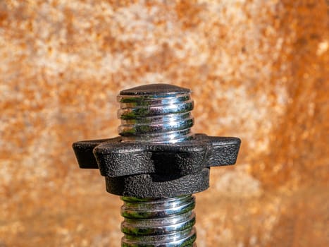 Iron bolt with thread and twisted nut. Threaded connection of parts with a bolt and a nut. Parts fastening technology. Locksmith accessories. Background image. Place for your text.