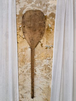 Old wooden shovel for baking bread in the oven. Wooden kitchen tool. Retro room interior. Old-fashioned background. Background image. Place for text.
