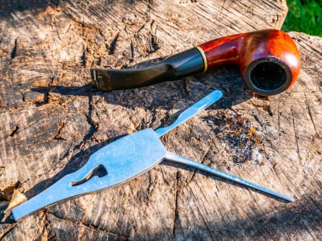 Tool for cleaning the smoking pipe from tobacco. Smoking pipe care. Smoker's tool. Human hand. Bad habits. Nicotine addiction. Nicotine in cigarettes. Background. Place for your text.