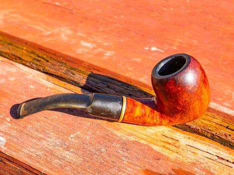 Wooden smoking pipe for tobacco on the table. Pipe for smoking tobacco. Smoker's tool. Wooden table. Bad habits. Nicotine addiction. Nicotine in cigarettes. Background image. Poster.