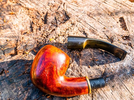 Disassembled smoking pipe for tobacco on a wooden table. Wooden pipe for smoking tobacco. Smoker's tool. Bad habits. Nicotine addiction. Nicotine in cigarettes. Place for your text. Background.