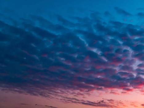 Red sunset on a cloudy blue sky with clouds. Pink evening dawn. Morning red pink sunshine dawn. Clouds in the blue sky. Pink morning dawn. Heavenly landscape. Space. Stratosphere.