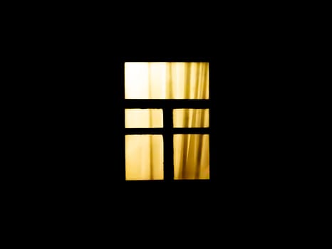 The window of the house glows in the dark at night. Electric light at night in the window of the house. Electric lighting. Night time. Background image. Place for your text. Poster.