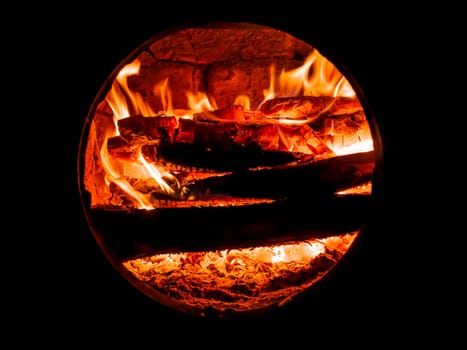 Red flame of fire in a wood stove. Fire sparks. Bright flame of a bonfire in the night. Fiery sparks above the wood. Fiery smoke. Heat in the furnace. Background image. Firefighter. Danger of arson.