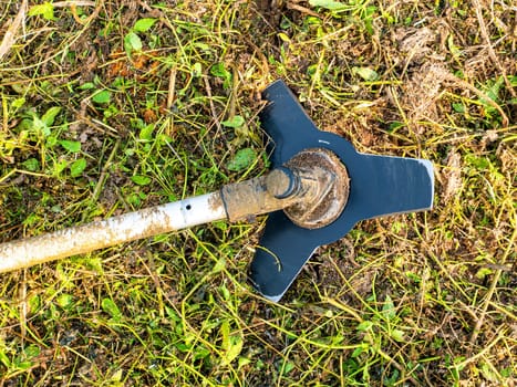 Lawn mower disc on a background of green grass. Trimmer for cutting green grass lawns. Mow the lawn sideways. Gardener's tool. Work tool. Gardening. Modern technologies. To work in the garden.