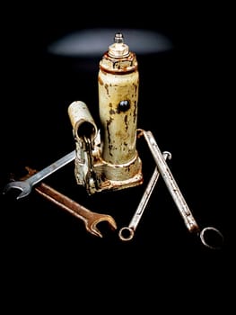 Hydraulic car jack and wrenches on a black background. Automotive hydraulic jack. Hand tool. Tire service. Car repair. Customer Service. Wheel replacement. Car mechanic tool. Place for text.