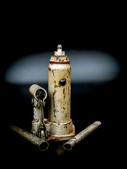 Old manual hydraulic car jack on a black background. Automotive hydraulic jack. Hand tool. Tire service. Car repair. Customer Service. Wheel replacement. Car mechanic tool. Place for text.