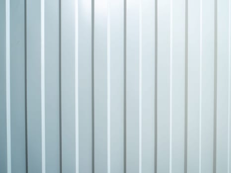 The texture of the striped corrugated metal surface is white. Vertical white stripes. The metal wall is painted white. Background image. Surface texture. Shadows. Place for your text. Poster.