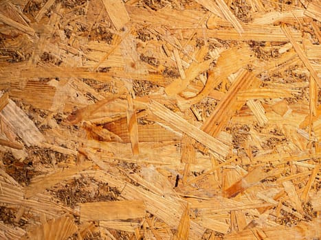 The structured texture of the wood fiber panel. Chipboard. Wood board texture. Timber processing industry. Board. Woodworking. Sawmill. Waste from wood processing. Background image.