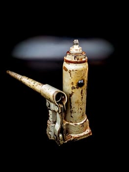 Old manual hydraulic car jack on a black background. Automotive hydraulic jack. Hand tool. Tire service. Car repair. Customer Service. Wheel replacement. Car mechanic tool. Place for text.