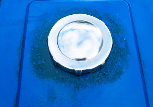 Nickel plated fuel tank cap in blue car color. Truck fuel tank cap. Place of the gulf of gasoline into the vehicle. Refueling a diesel agricultural tractor. Background image. Place for your text.