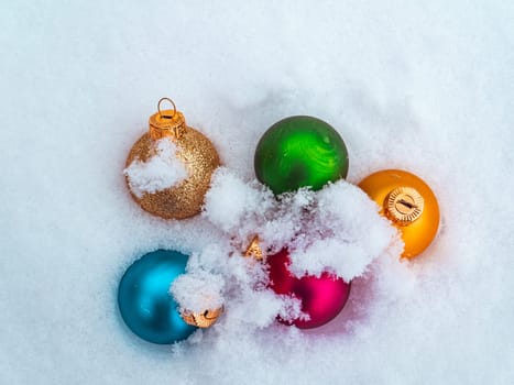Christmas tree toys colored balls on white snow. Christmas holidays. New Year. Loose winter snow. New Year holidays. Winter vacation. White background. Place for text. Greeting card. Invitation.