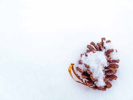 Christmas toy pine cone spruce on white snow. Pine cone. Christmas holidays. New Year. Loose winter snow. New Year holidays. Winter vacation. Place for text. Greeting card. White background.